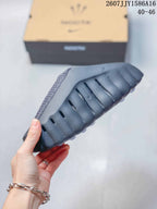 Side and outsole view showing the sculpted profile, deep grooves, and textured black-gray sole.