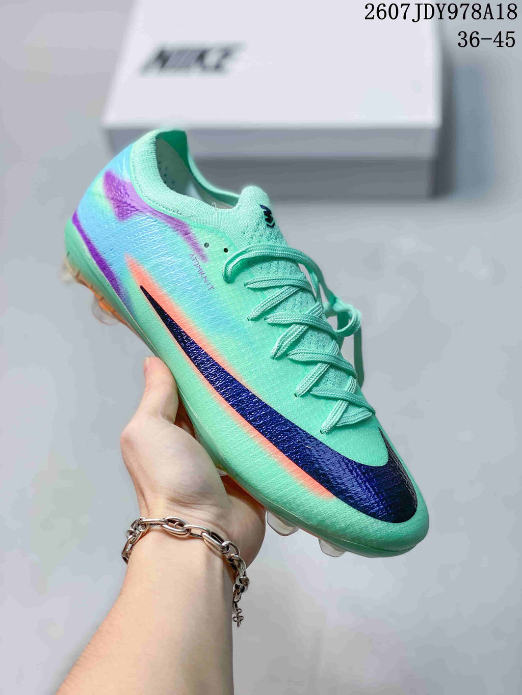 Mint green Nike soccer cleat with purple, orange and dark blue graphic accents.