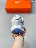 Rear view of a light gray Nike running shoe showing the padded heel, white midsole, and blue outsole section.