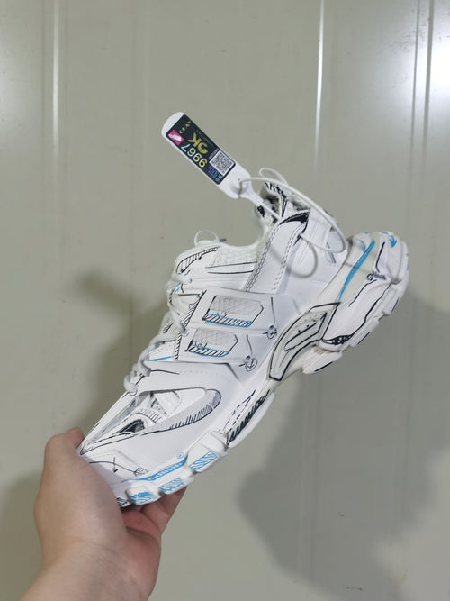 White, black, and blue track sneaker shown from an angled side view, highlighting layered panels and sculpted sole details.
