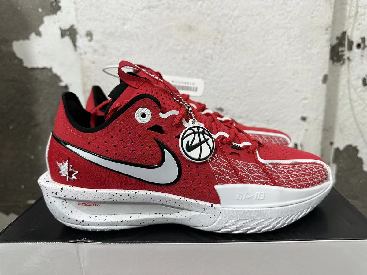 Side view of a red basketball shoe with a large white Swoosh, maple leaf detail, and speckled sole.