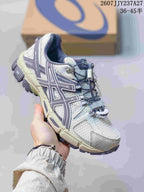 Three-quarter side view showing the white and gray upper, muted purple accents, and rugged outsole.