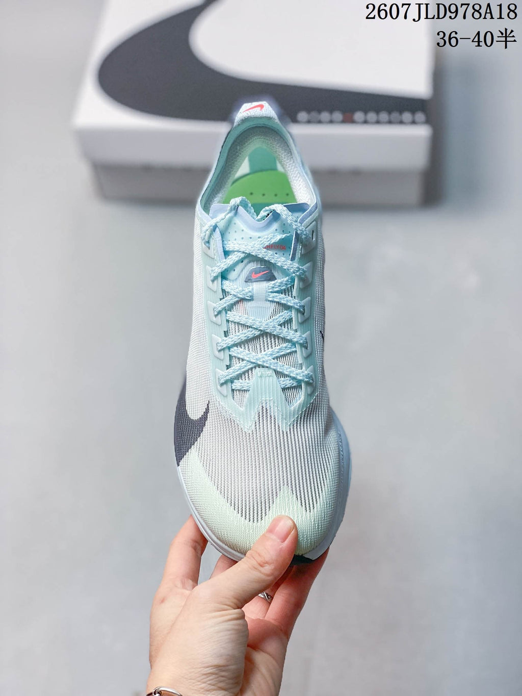 Top view of the sneaker showing the pale blue laces, textured upper, dark Swoosh, and green insole.