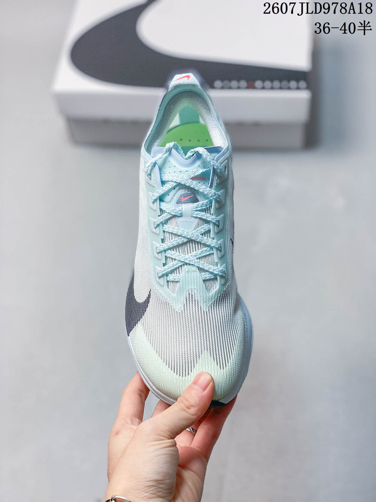Top view of the sneaker showing the pale blue laces, textured upper, dark Swoosh, and green insole.