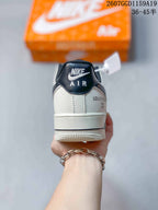 Rear view of a white sneaker showing a black padded collar, Nike Air branding, and decorative heel lettering.
