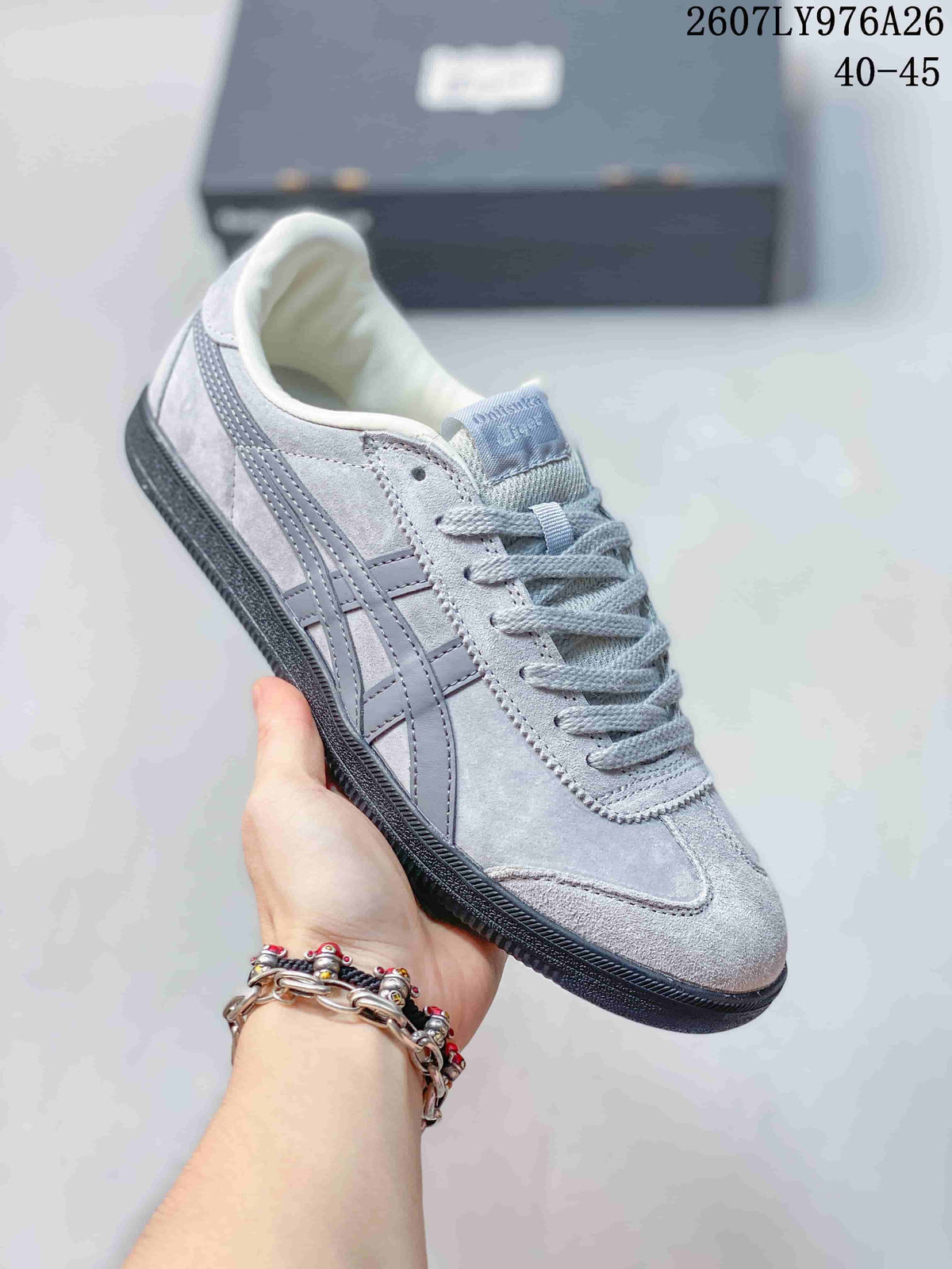 Close-up side view of a light gray Onitsuka Tiger Tokuten sneaker with tonal stripes and dark outsole.