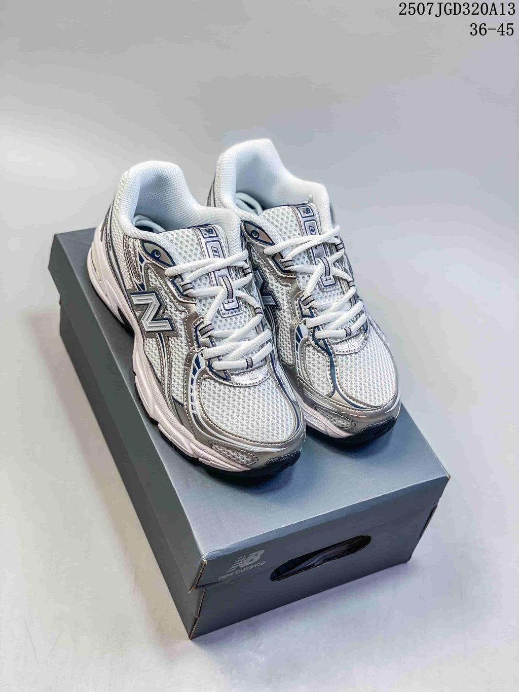 Pair of white, silver, and navy New Balance 740 sneakers displayed on a shoebox.