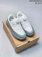 Pair of white and gray DESCENTE low-top sneakers displayed on a shoebox, showing the round dial closures and padded collars.