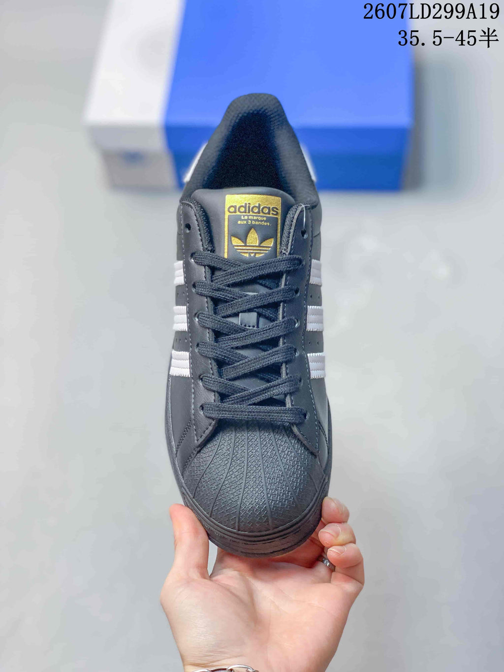 Top view of the sneaker showing black laces, Trefoil tongue branding, and the textured shell toe.