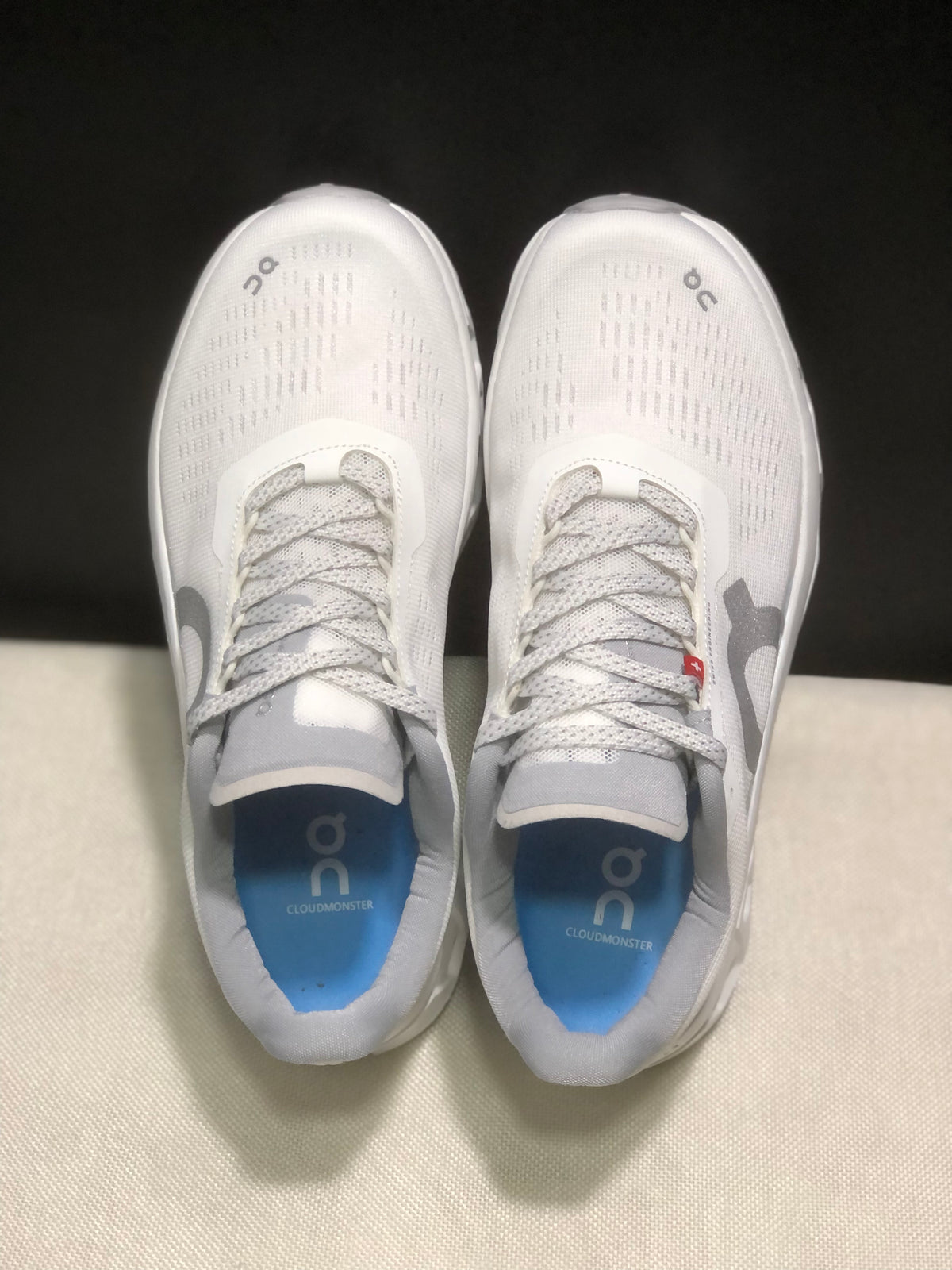 Top view showing the lace-up construction, perforated-style upper detailing, and blue insoles marked Cloudmonster.