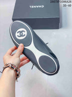 Underside of a black-and-white trainer showing the two-tone outsole and circular traction panels, with a Chanel-marked box in the background.