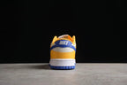 Rear view of a Nike sneaker showing the blue heel detail, white heel panel, and wheat gold lower section.