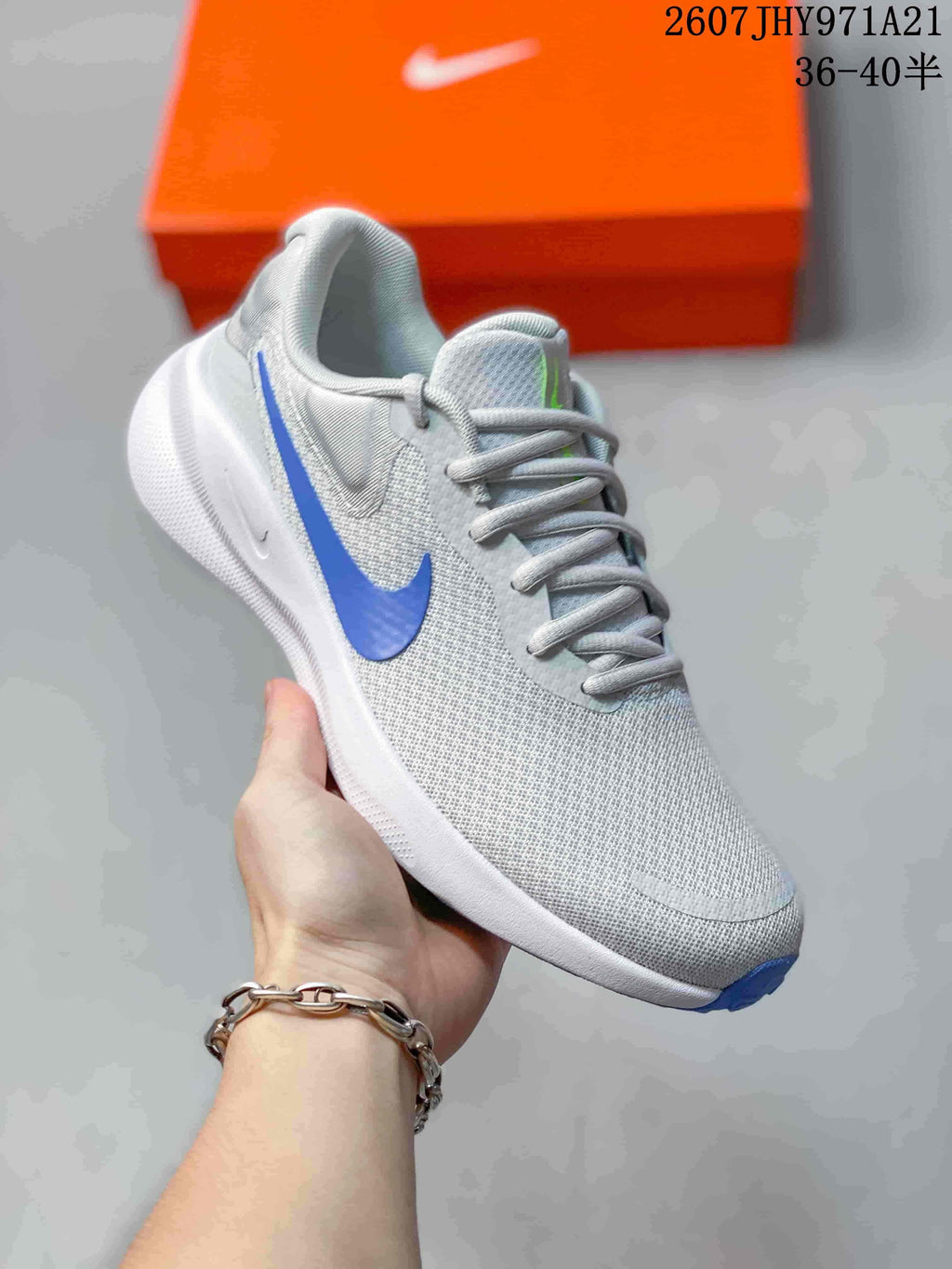 Angled side view of a light gray Nike running shoe with a blue Swoosh, white midsole, and blue outsole tip.