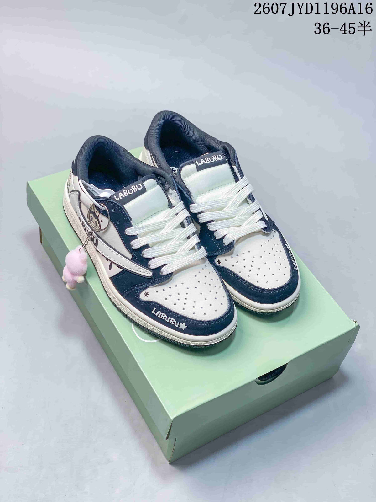 Pair of black-and-white Jordan low-top sneakers displayed on a mint-green shoebox, showing Labubu tongue graphics and a plush side charm.