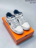 Pair of beige and gray Nike SB Dunk Low sneakers with patterned panels and an orange box.