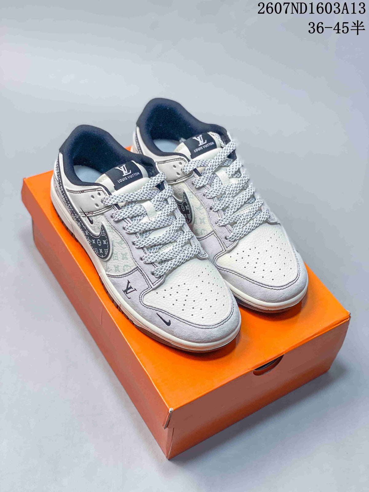 Pair of beige and gray Nike SB Dunk Low sneakers with patterned panels and an orange box.