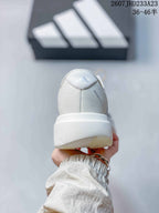 Rear view of the white sneaker showing the padded heel, textured upper, and thick sole.