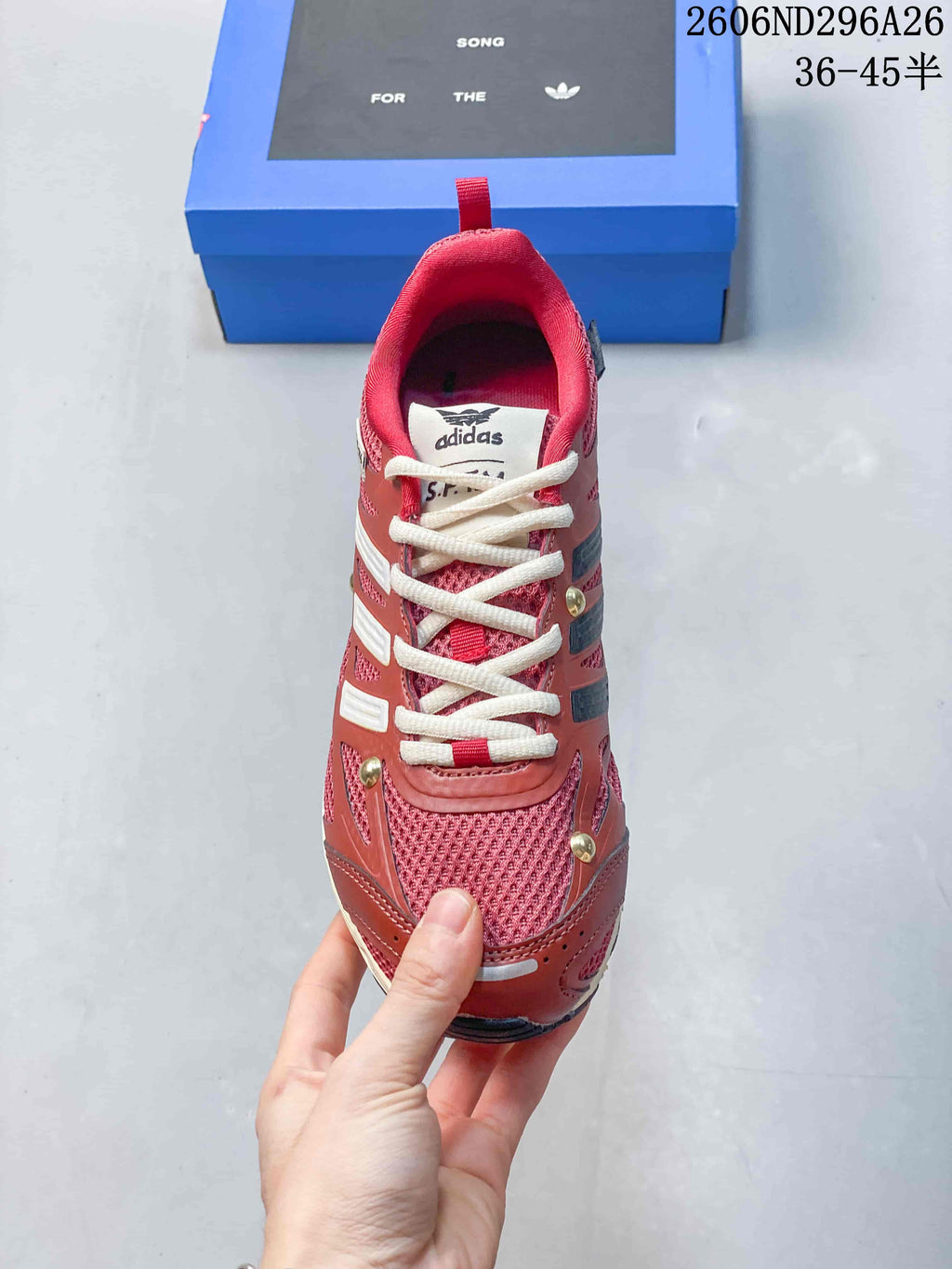 Top view of the sneaker showing the red mesh toe area, cream laces, padded tongue, and Adidas branding.
