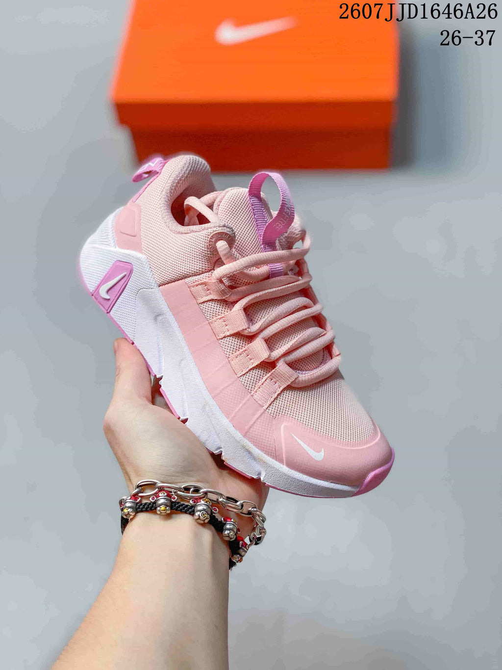 Angled side view of the pink and white children's training shoe showing the layered upper and patterned outsole.