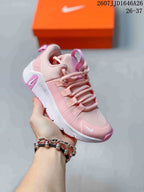 Angled side view of the pink and white children's training shoe showing the layered upper and patterned outsole.