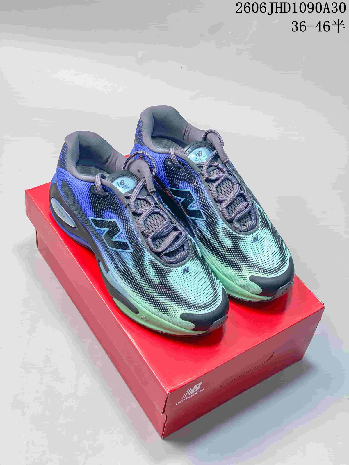 Pair of blue, mint, and charcoal New Balance AC Runner shoes on a red box