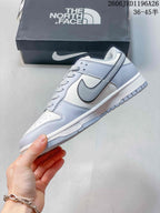 Side view of a white and light gray low-top sneaker with contrasting Swoosh detail.
