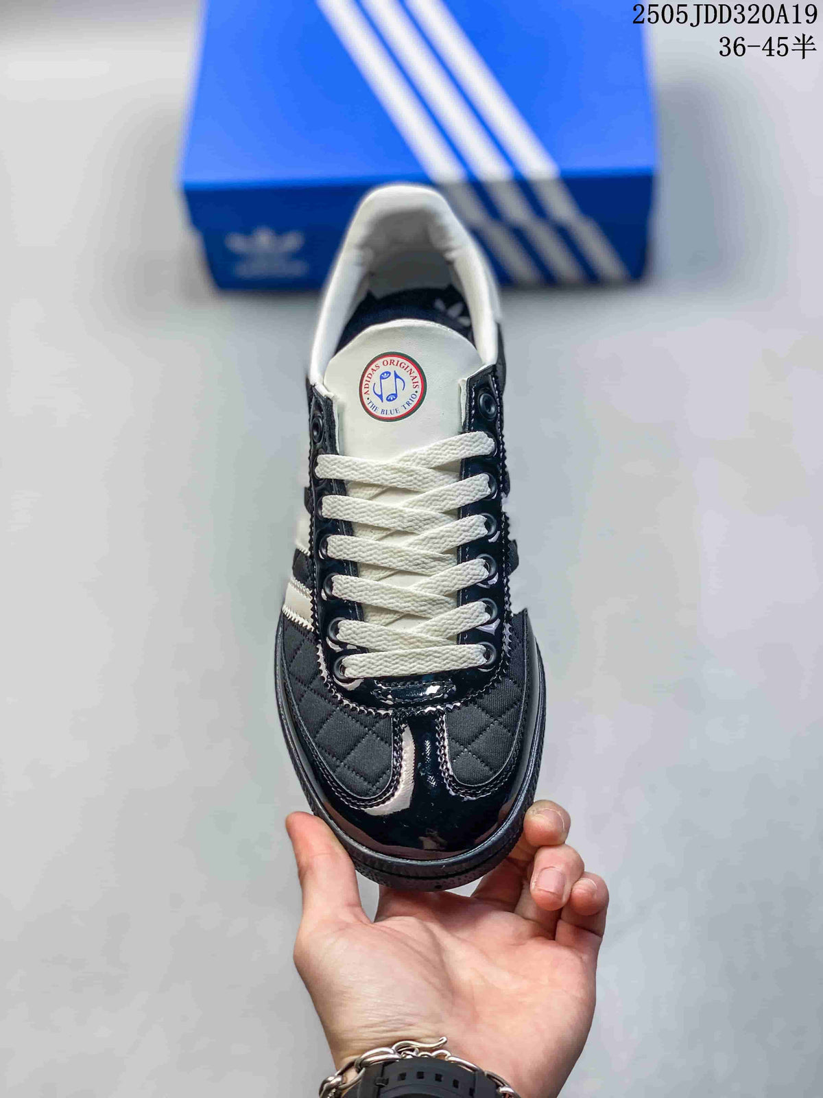 Top view showing white laces, black quilted panels, white stripes and glossy black toe detailing.