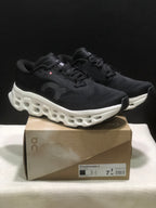 Pair of black and white On Cloudmonster 3 sneakers displayed on a branded shoe box.