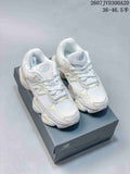 Pair of white and light cream New Balance 9060 sneakers displayed on a shoebox.