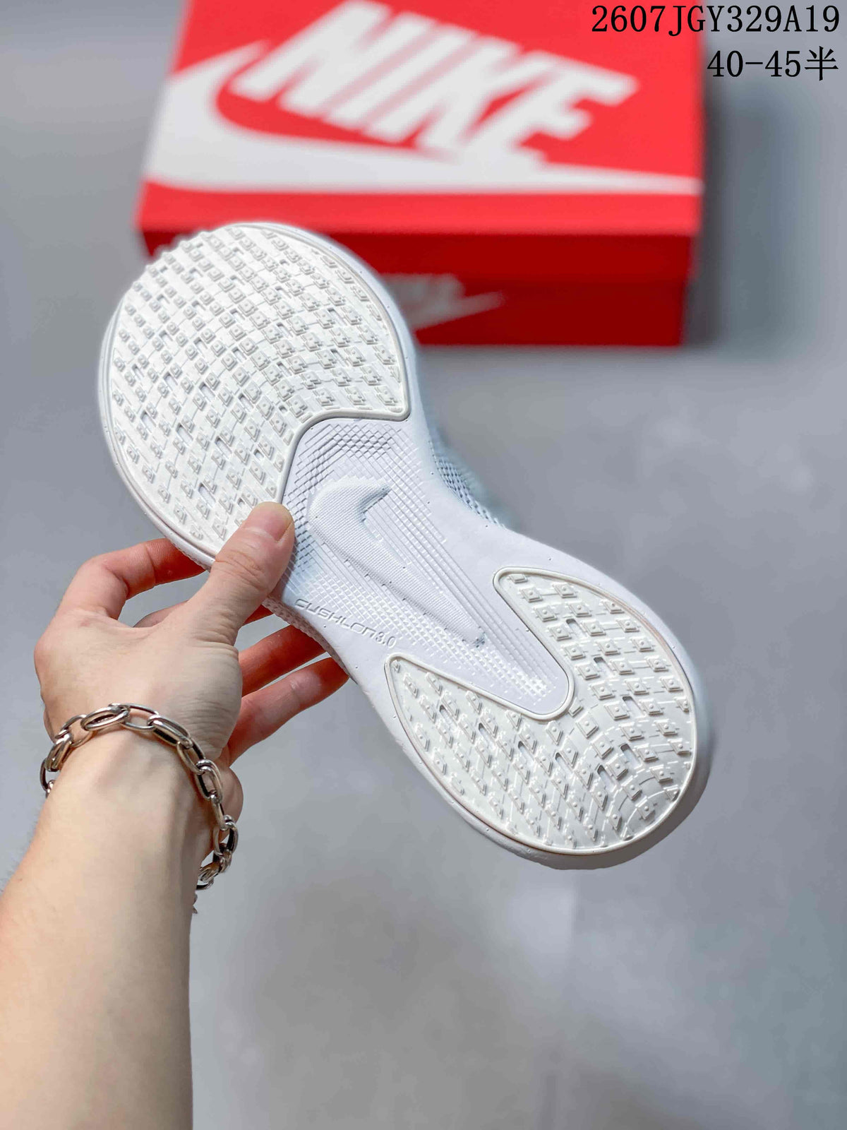 Underside view of a white sneaker showing the textured outsole and raised traction pattern.