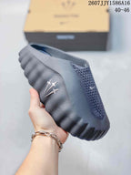 Side view of a black and gray closed-toe slide showing the perforated upper, sculpted sole, and side branding detail.