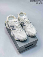 Pair of white New Balance 9060-style mule sneakers displayed on a shoe box, with navy branding and pale yellow-green accents.