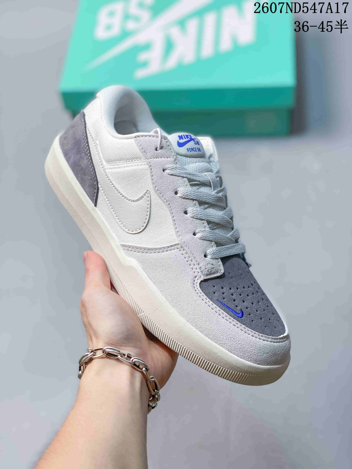 Angled side view of the Nike SB Force 58 sneaker showing the white and grey upper, blue tongue detail and textured outsole.