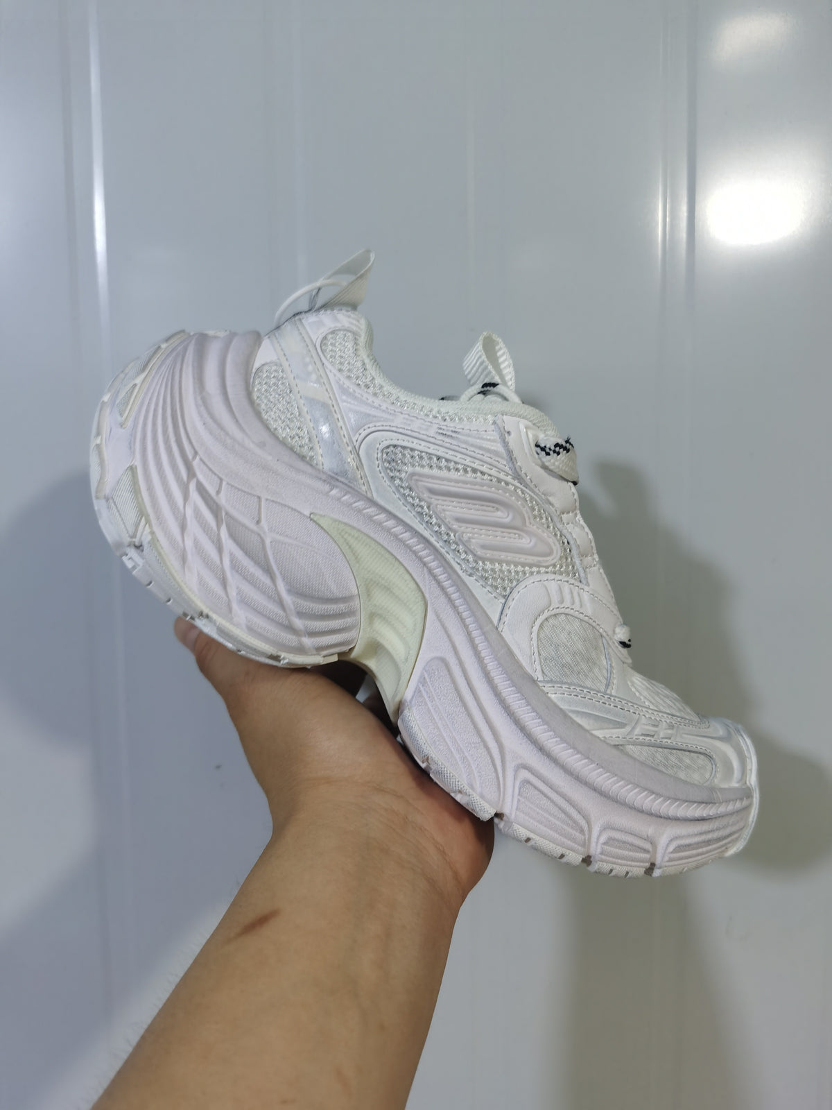 White chunky sneaker shown from the outer side, highlighting layered panels, mesh sections, and a sculpted sole.