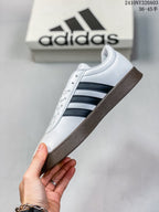 Side view highlighting the white upper, black side stripes, textured toe panel, and gum-colored sole.