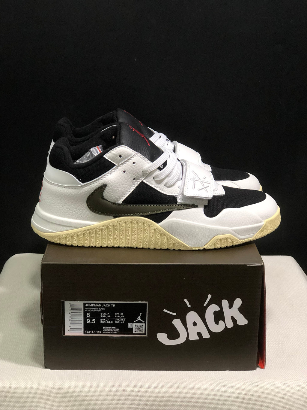 Side view of the white and black sneakers showing the dark side Swoosh, forefoot strap, and sail-colored outsole.