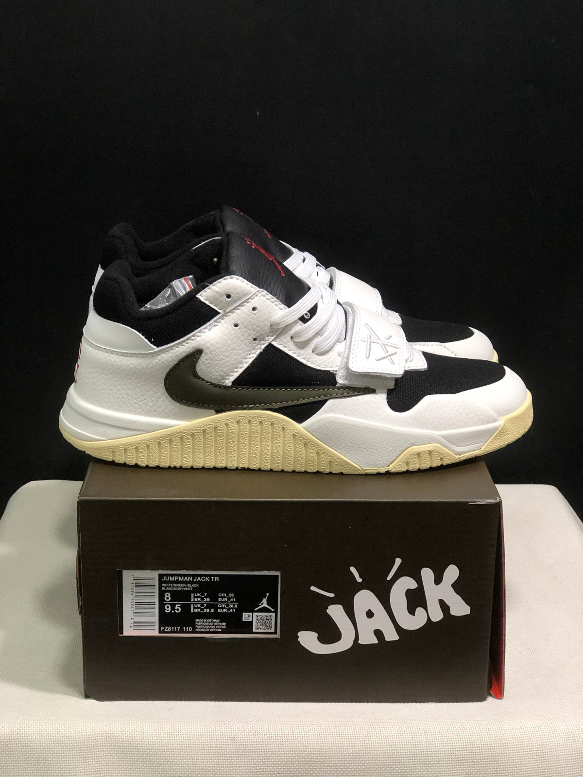 Side view of the white and black sneakers showing the dark side Swoosh, forefoot strap, and sail-colored outsole.