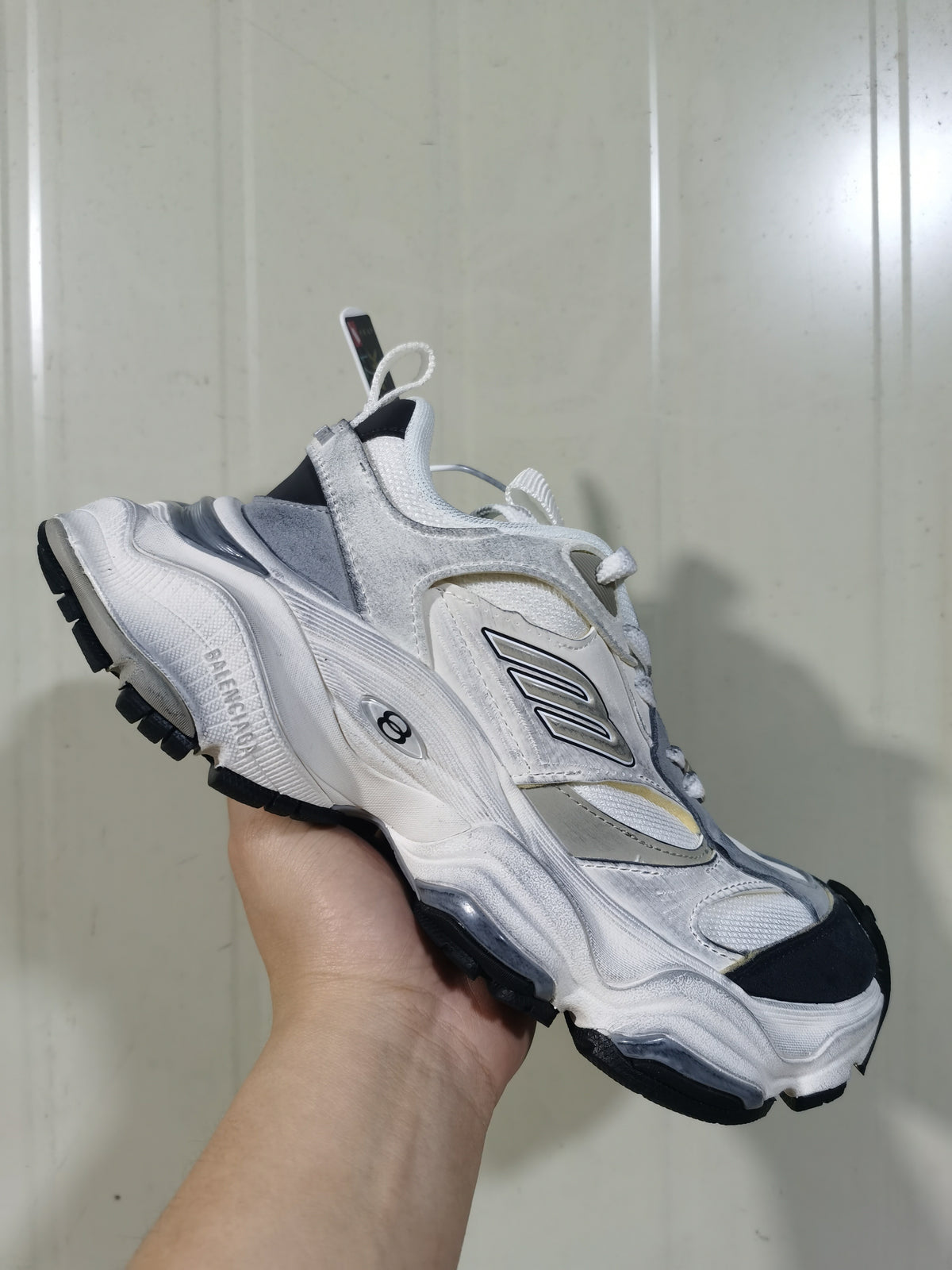 Close angled view of the white and grey Balenciaga cargo sneaker showing layered panels, lace-up fastening, and chunky sole.