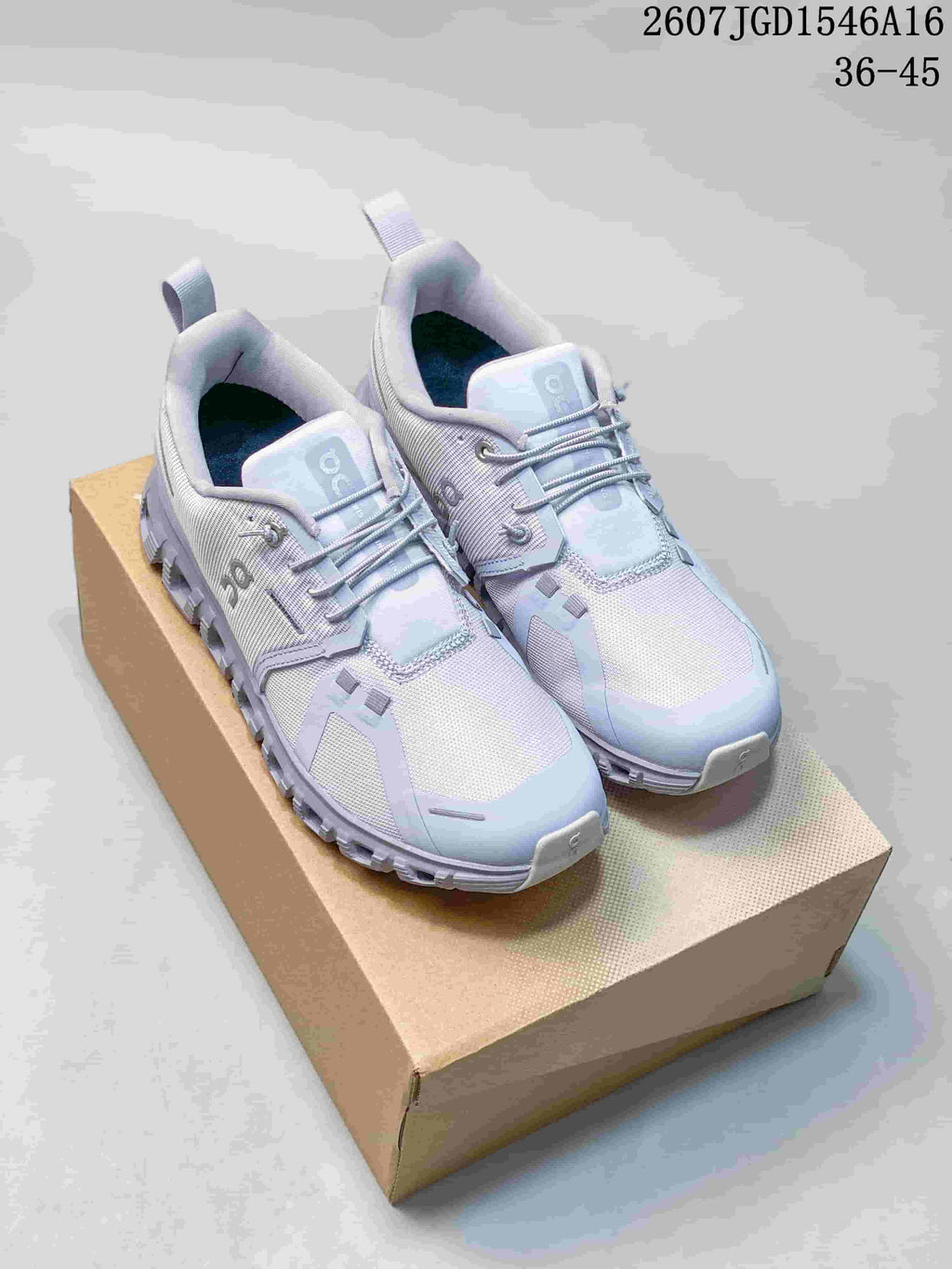 Pair of light gray On sneakers displayed on a cardboard box, showing the upper, laces, side branding and segmented outsole.