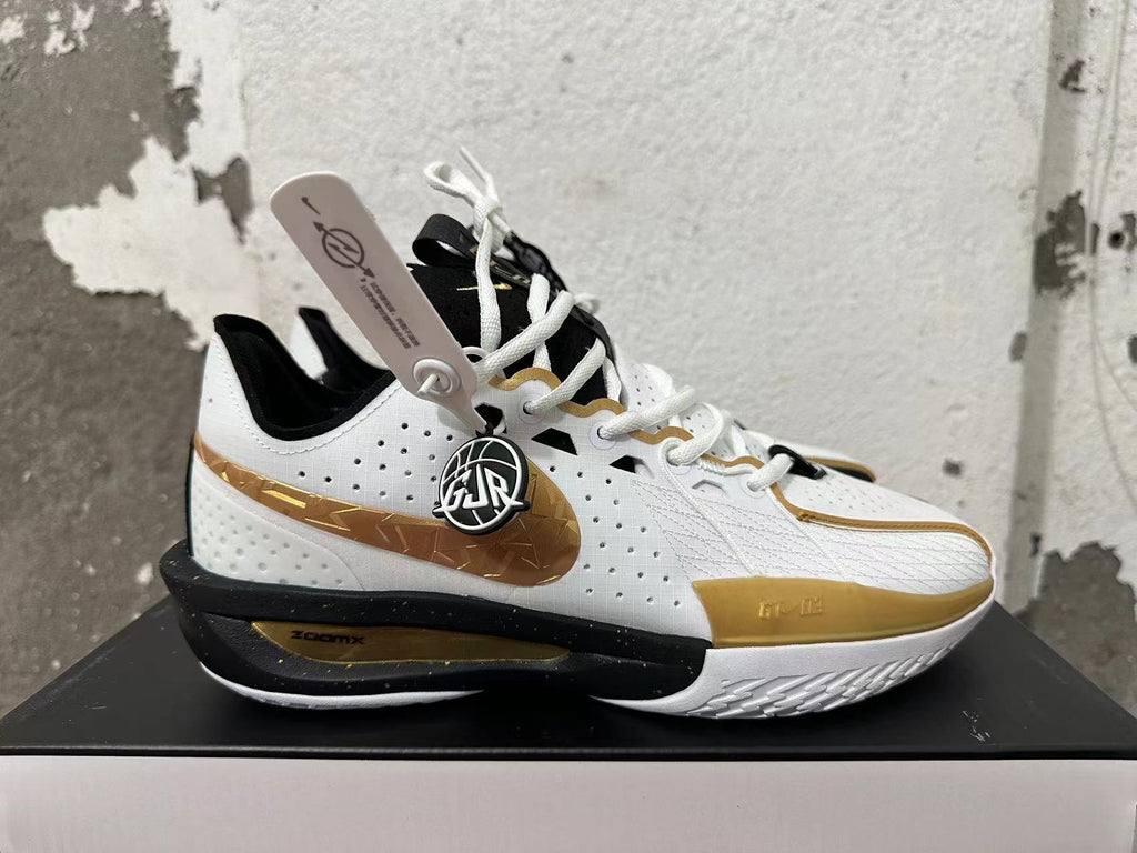 Side view of a white Nike basketball shoe with a metallic-gold Swoosh, perforated panels, and a black midsole.