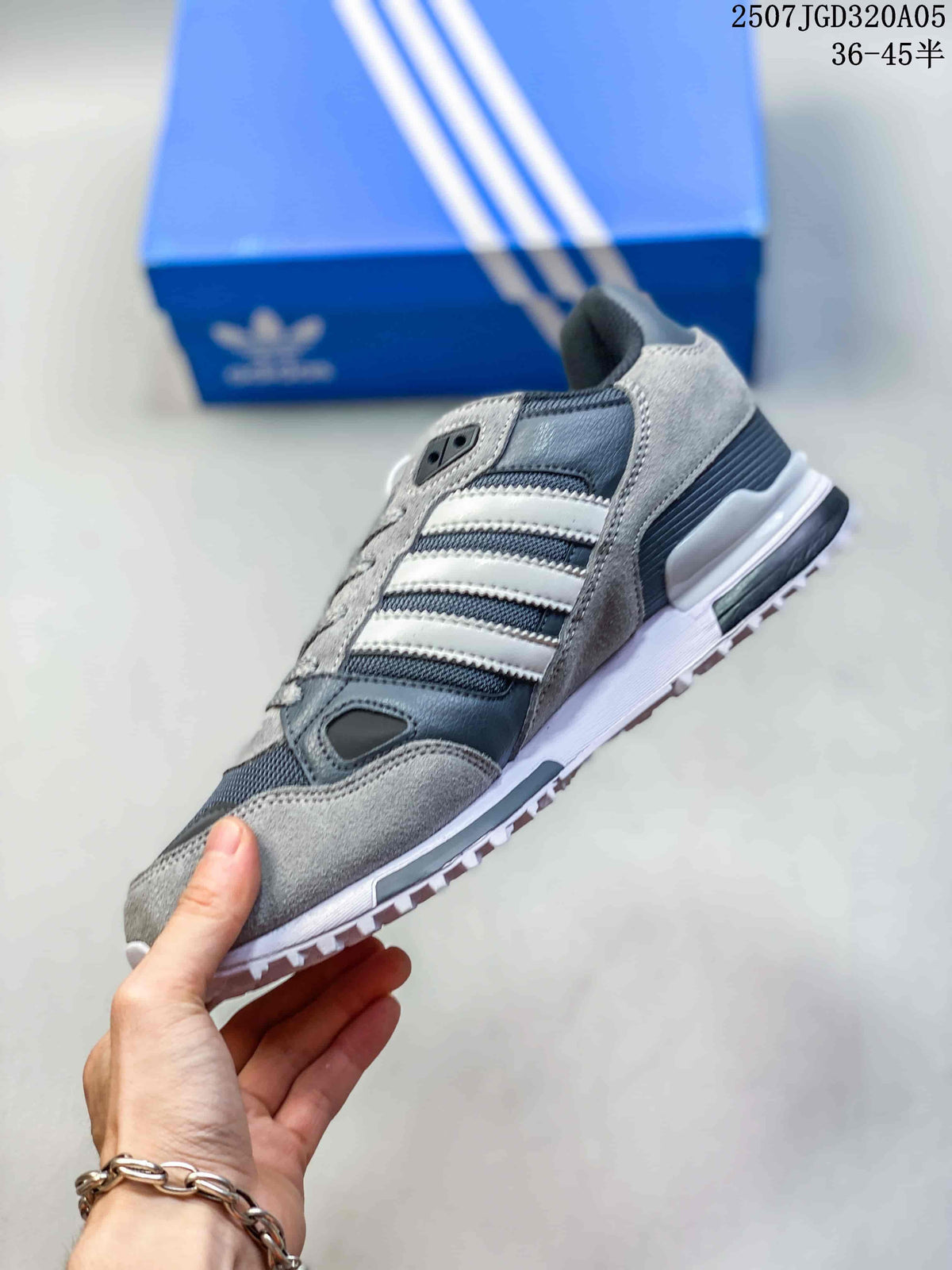 Side view of a grey adidas ZX 750 sneaker with white stripes and textured outsole.