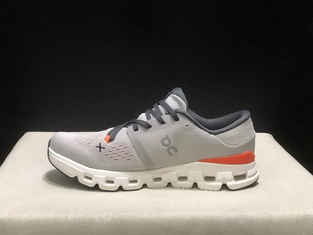 Side profile of one silver and flame shoe showing the On logo, lace-up construction, and segmented sole.