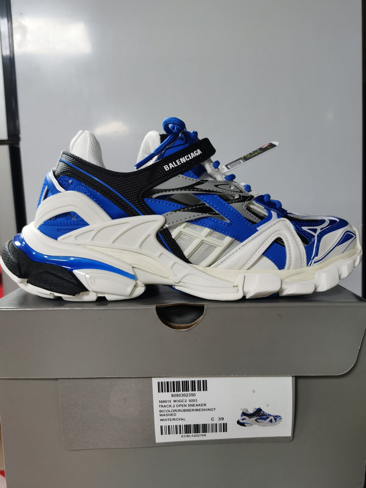 Balenciaga Track.2 open sneaker in white, royal blue and black, photographed on its shoe box with the box label visible.