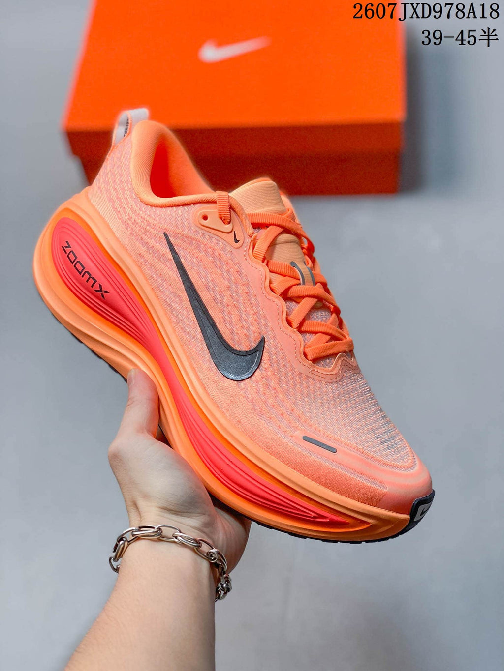 Orange Nike Vomero Plus running shoe with a darker swoosh and contrasting red-orange midsole details.