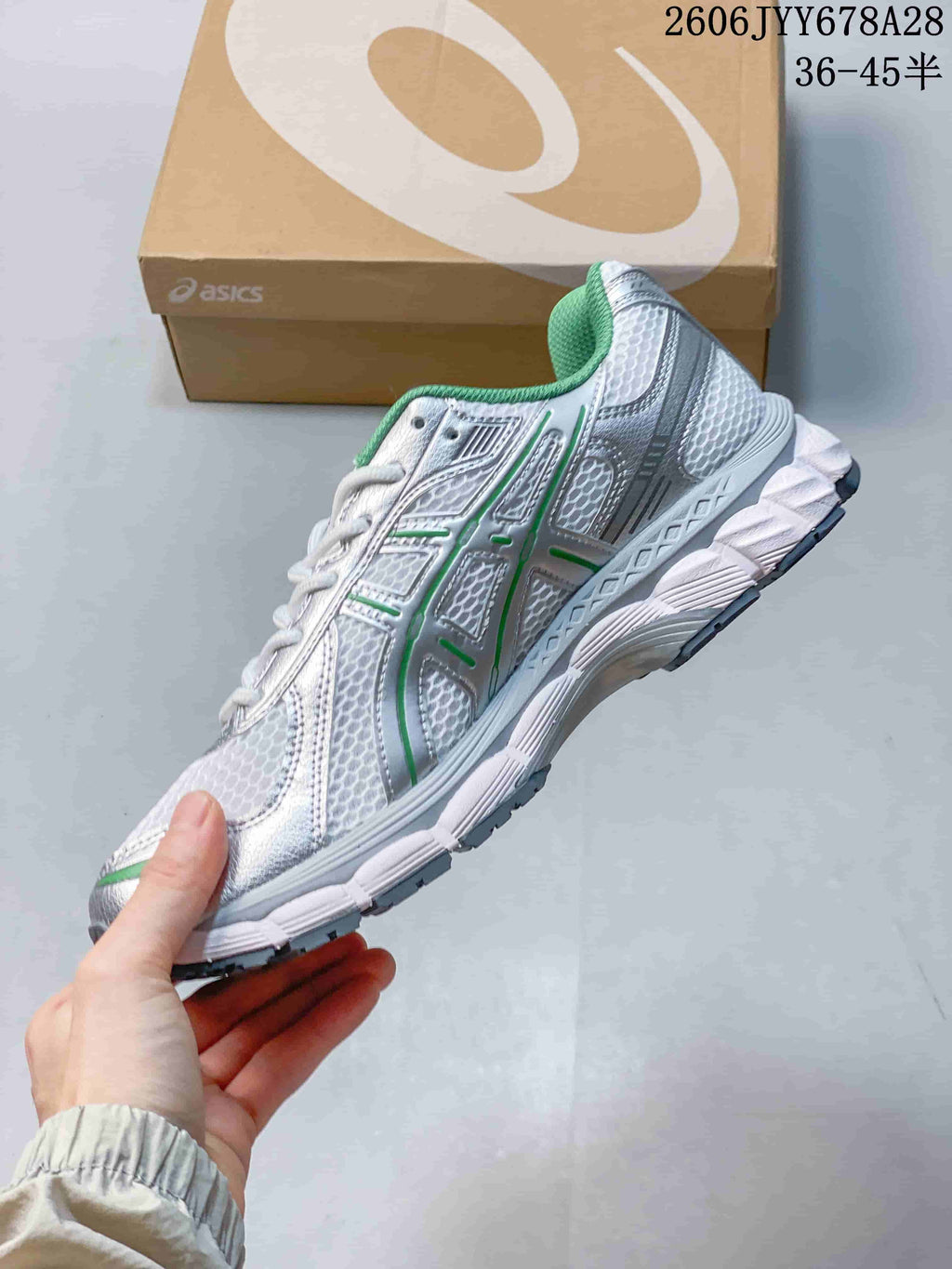 Side view of the silver-toned running shoe with green accents and textured upper.