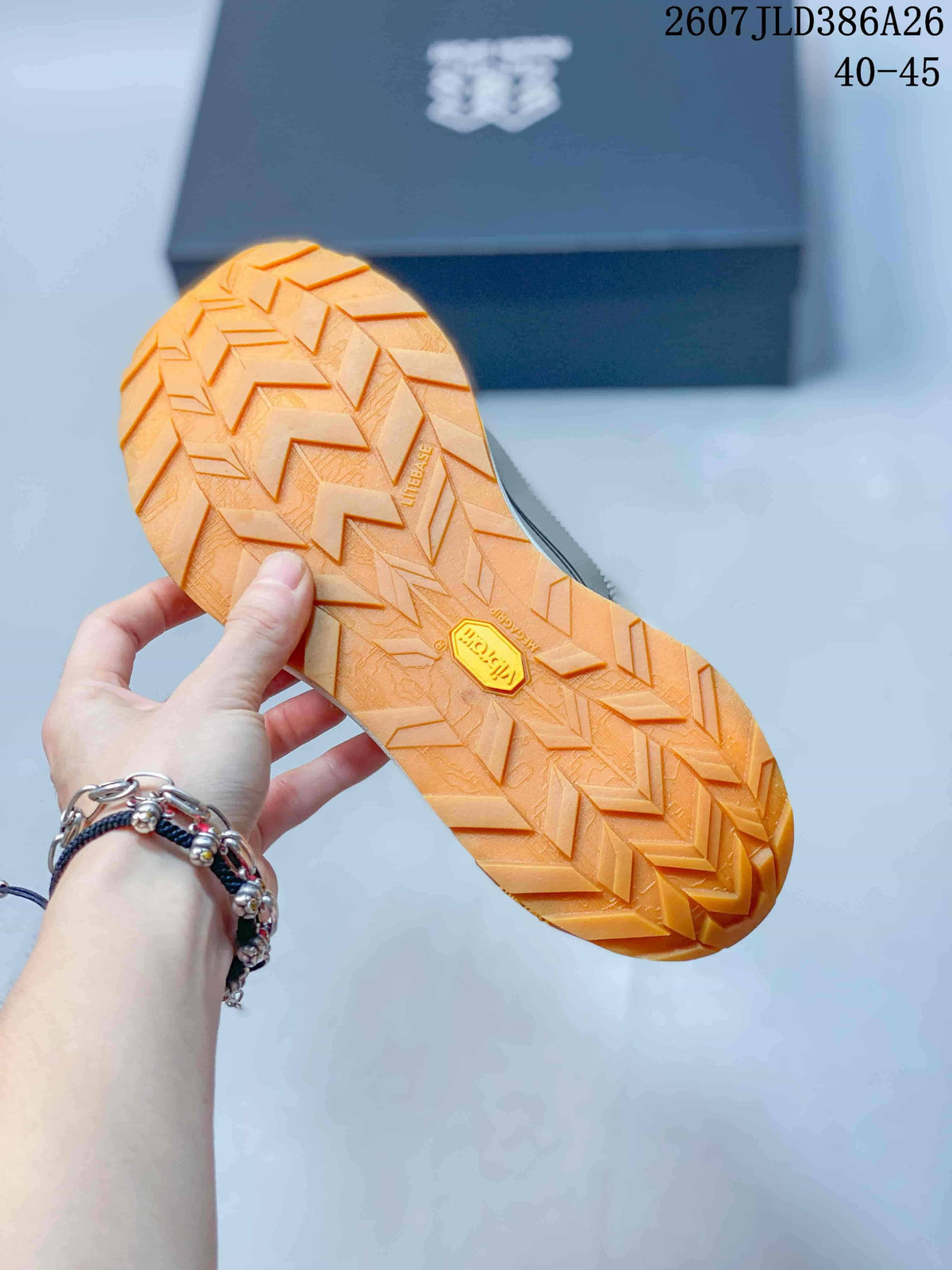 Close view of the orange outsole showing a pronounced chevron lug pattern and central brand detail.