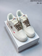 Pair of white Nike Air Force 1 '07 LV8 low-top sneakers with brown laces and accents on a shoebox.