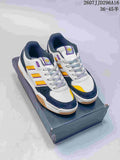 Pair of adidas Tekkira Cup sneakers on a shoebox, showing the white, navy, yellow, and purple color scheme.