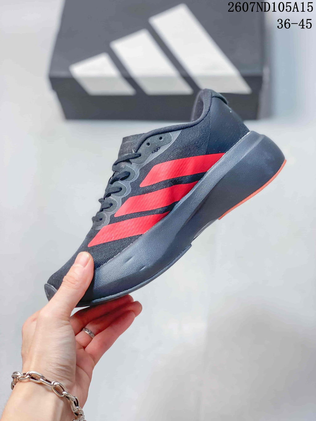 Side profile of the black low-top sneaker with red Adidas stripes and a thick contrasting sole.