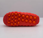 Underside view showing the orange circular traction pods across the orange-red outsole.